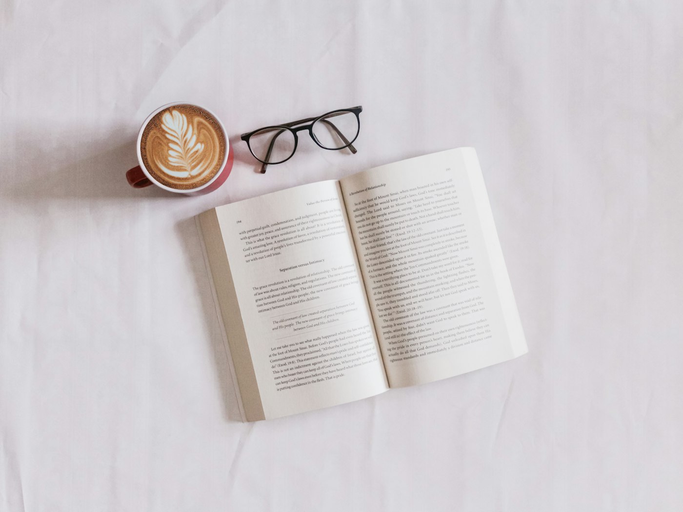 Placeholder photograph of a book, reading glasses, and coffee on a pale cloth.